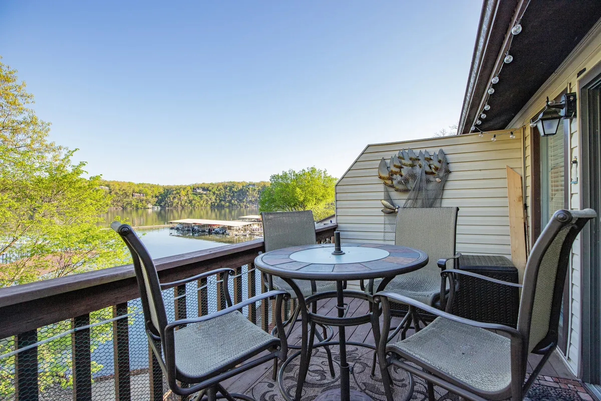 The hero image features an inviting outdoor dining table overlooking a tranquil lake, with a whimsical decorative fish sculpture adding a touch of lakeside charm. The serene setting suggests opportunities for sunrise breakfasts or star-gazing evenings, all framed by beautiful water views and peaceful natural surroundings.