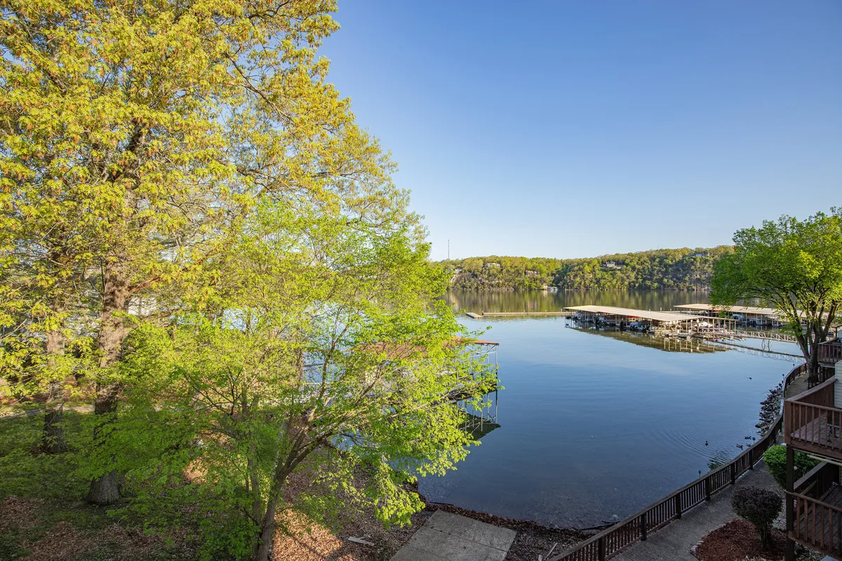 This image features a serene lake with a dock extending out over the water, surrounded by trees and an open sky. The setting evokes feelings of relaxation, outdoor adventure, and connection with nature.