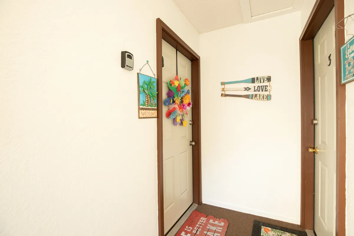 A bright entryway welcomes guests into the home, featuring a colorful wreath on the door, cheerful welcome sign, and decorative wall accents that instantly set a festive, inviting tone. The space radiates warmth and excitement, hinting at the memorable experiences ahead.
